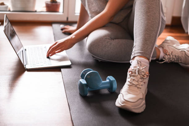 istock Training, Fitness At Home. Sporty man doing yoga plank while watching online tutorial on laptop, exercising in living room. woman multitasking remote work indoors lifting weights dumbbells 1223393037