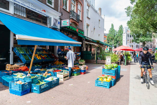 Amsterdam, Netherlands - September 8, 2018: Vendor in a fruit and vegetable shop with people around in Amsterdam, Netherlands