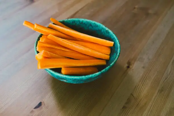 May 6, 2020 - Warsaw, Poland: carrots sticks in a bowl for children's' party - healthy veggie snack, raw vegetables for Hay diet, raw food diet, dieting and healthy eating, close up view on a wooden table