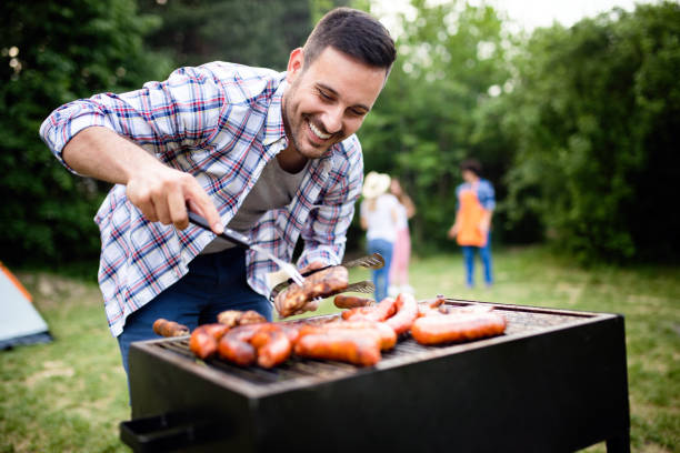 istock Handsome male preparing barbecue, grill outdoors for friends 1223395327