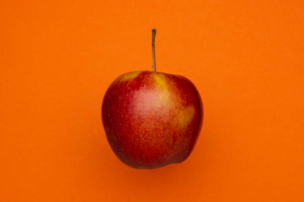 istock Red apple isolated on an orange background. 1223396390