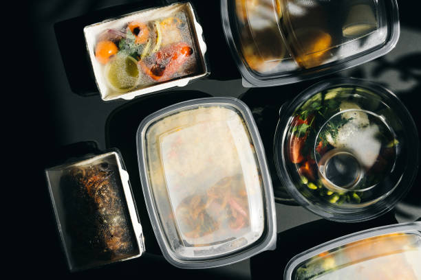 Delivery service food in plastic lunch boxes on a black background. Low key, healthy food.