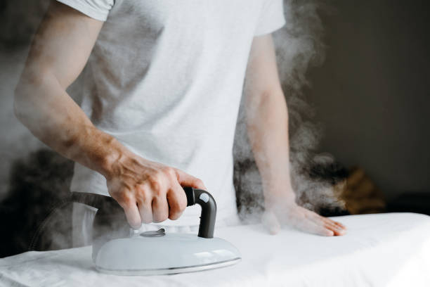 istock Man ironing bed linen on iron board at home. 1223398099