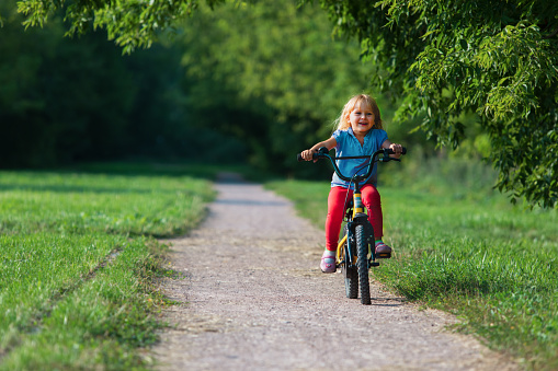 cute happy little girl riding bike in nature, child exerice outdoors