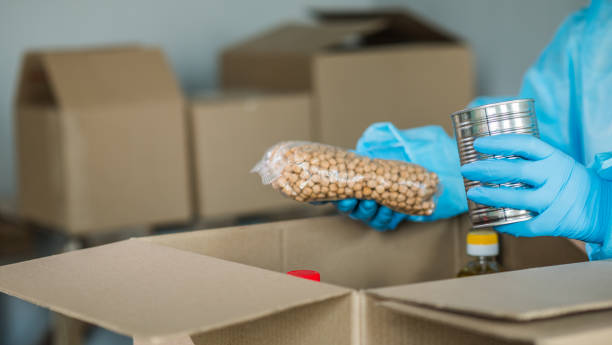 istock Man in protective suit packs grocery set into cardboard box 1223406867