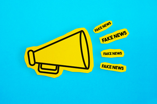 El dibujo del megáfono en el papel amarillo cortado hace el anuncio de las noticias falsas. photo