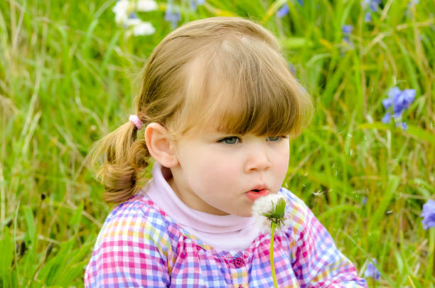 istock attractive girl blowing on a dandelion to make a wish 1223407520