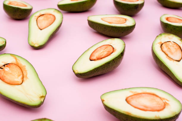 istock Avocado natural color and condition divided in half on a pink background. 1223413030
