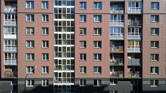 Facade of a new multi-story residential building. Rising prices for the purchase, sale and rental of real estate. Economy class apartments. Comfortable housing. Cityscape. City living. Windows.