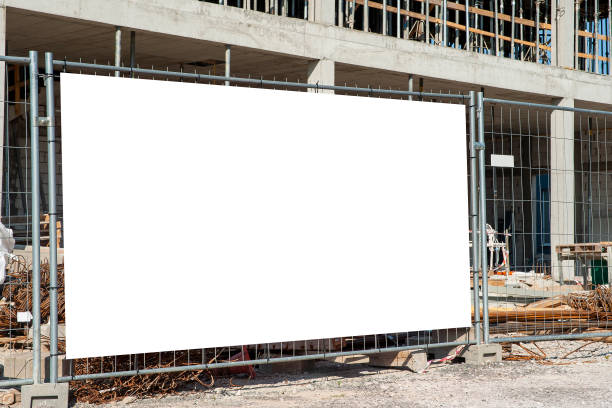 Blank white banner for advertisement mounted on the fence of construction site on a sunny day. Blank white banner for advertisement mounted on the fence of construction site on a sunny day. city street street man made structure place of work stock pictures, royalty-free photos & images