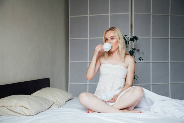 verticale d’un beau petit déjeuner blond de femme dans le matin de chambre à coucher - back against the wall photos et images de collection