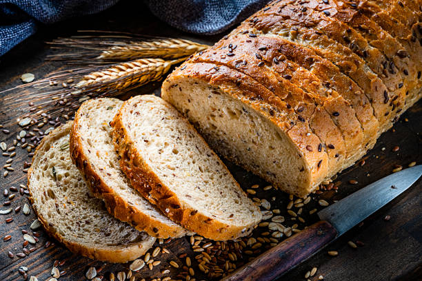 Wholegrain and seeds sliced bread Healthy food: wholegrain and seeds sliced bread shot on rustic wooden table. Predominant color is brown. High resolution 42Mp studio digital capture taken with Sony A7rII and Sony FE 90mm f2.8 macro G OSS lens slice of bread stock pictures, royalty-free photos & images