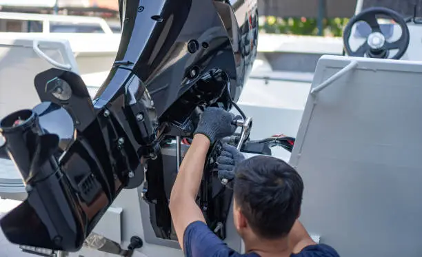 Mechanic is installing speed boat engine , a new engine on an aluminum boat.
