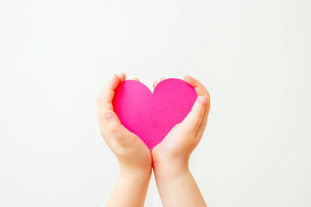 istock Paper pink heart in child's hands. 1223426449
