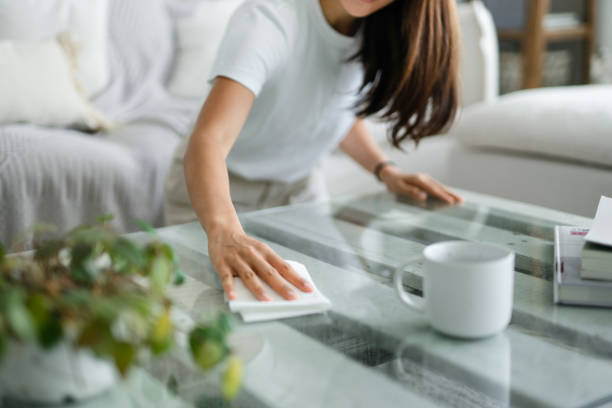 abgeschnittene aufnahme von jungen asiatischen frau aufräumen das wohnzimmer und wischen die couchtisch-oberfläche mit einem tuch - coffee table living room indoors comfortable stock-fotos und bilder