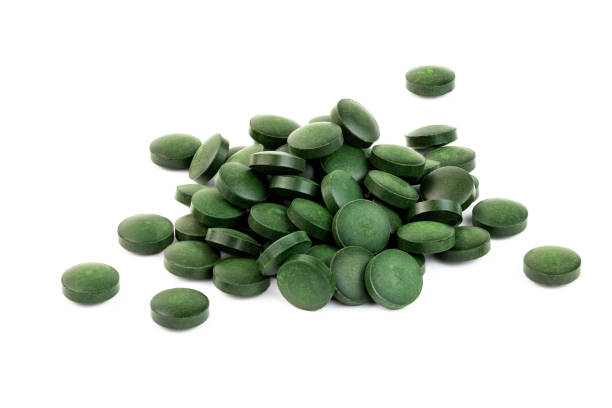 흰색 배경에 고립 된 녹색 스피룰리나 알약의 작은 더미 - spirulina bacterium green vitamin pill medicine 뉴스 사진 이미지