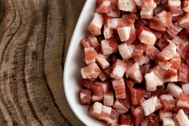 italian pancetta, bacon cubes, diced ham, cutted pork in square white plate on wooden textured surface. - pancetta imagens e fotografias de stock