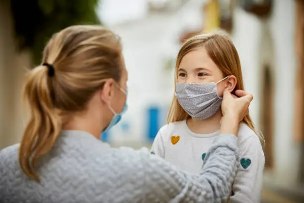 Photo of A mother helps daughter put home made face mask for COVID-19