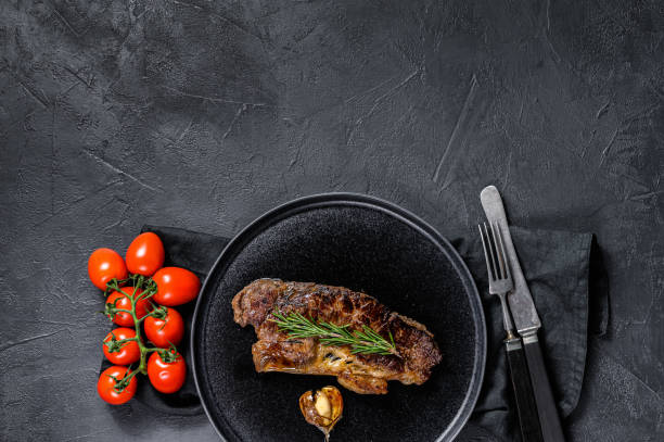istock Beef strip loin steak on black background. Space for text. Marble beef. 1223428438