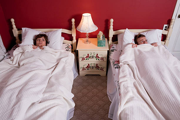 Young couple hiding under bedclothes  twin bed stock pictures, royalty-free photos & images