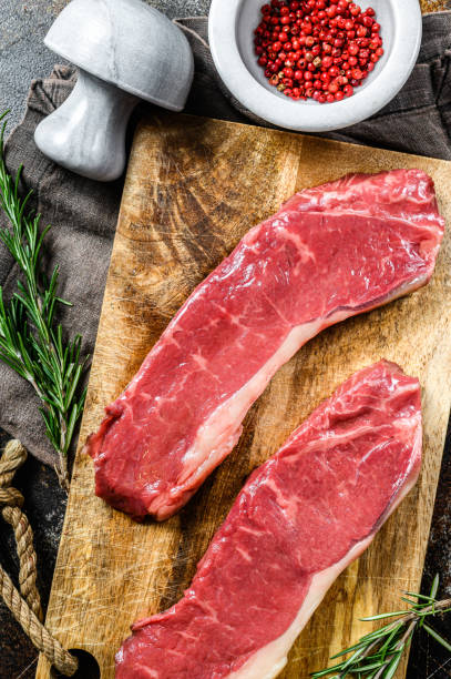 istock Fresh meat, marbled beef, raw strip loin steak. Dark background. Flat lay 1223429849