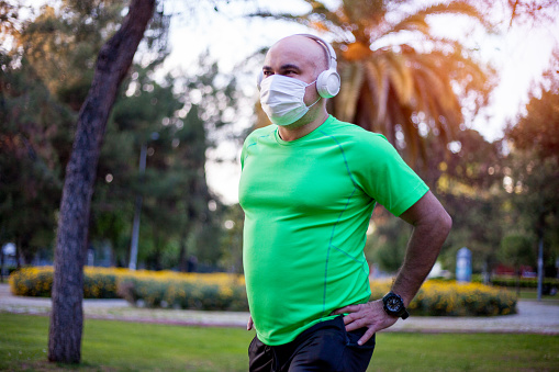 Man is stretching at park wearing protection mask during the covid-19