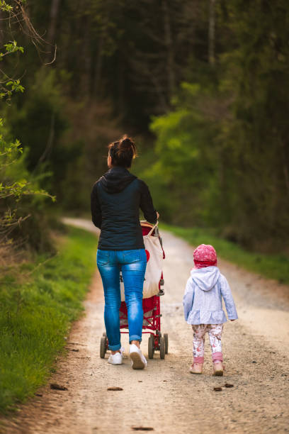istock Young mother and child next to red stroller walks on forest path in rural area 1223430392