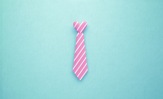 Heart shaped pink and white striped tie sitting over turquoise background. Horizontal composition with copy space. Father's Day concept.