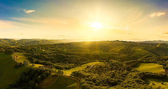Gorgeous sunset over beautiful green vineyards. Aerial panorama sunset over Austrian grape hills in spring. Wine culture in south styria, tuscany like tourist famous spot.