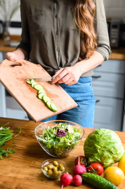 istock Girl throws sliced fresh cucumber in salad 1223442061
