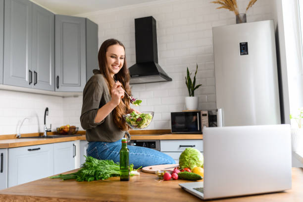 istock Woman eats and looks at the laptop screen 1223442083
