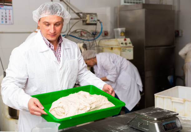 Bakers portioning dough with bench cutter at bakery
