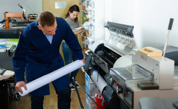 istock Worker loads new roll of paper into the plotter 1223442866