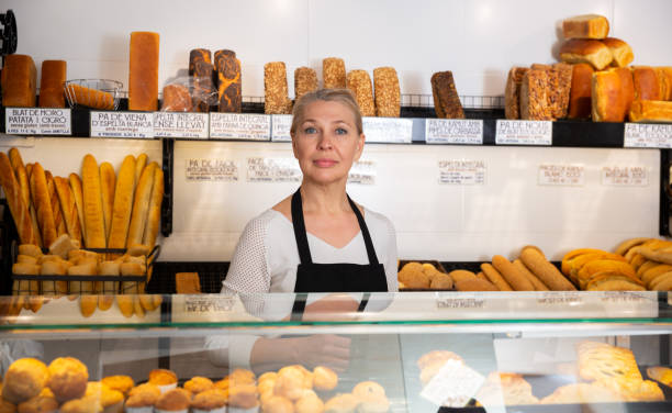 istock Female bakery employee offering bread and different pastry for sale 1223442898