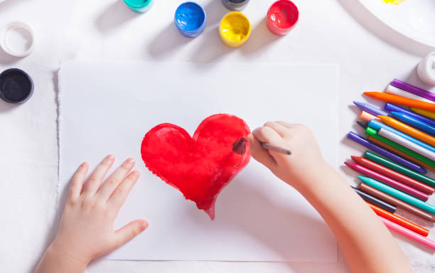 un niño dibuja el corazón rojo con pinturas de colores en el papel. - pencil colors heart shape paper fotografías e imágenes de stock