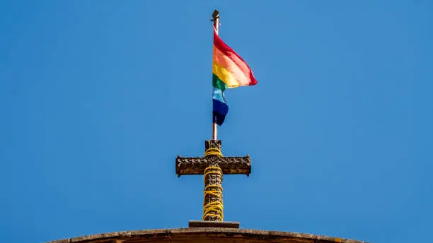 Photo of flag of cusco. rainbow flag on top of a church