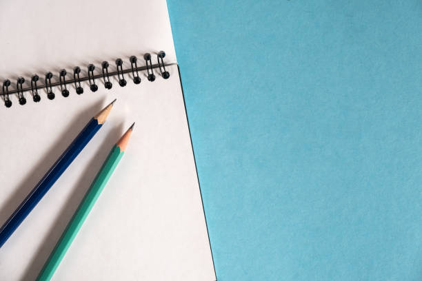 istock pencils and spiral notebook on a pastel light background. Notebook with blank clear page on the table. 1223452323