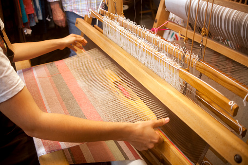 Agolada,Pontevedra, Spain-July 6,2019: Close-up view of old traditional loom during craft traditional festival, young woman's hands working, thread from weaving machine. AGolada, Pontevedra province, Galicia, Spain.