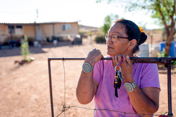uma avó navajo em pé ao lado do portão de sua casa em monument valley, arizona, coronavirus - senior women depression sadness women - fotografias e filmes do acervo