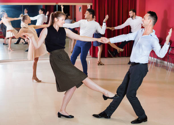 Adult dancing couples enjoying active swing Adult happy cheerful positive dancing couples enjoying active swing in modern studio swing dancing stock pictures, royalty-free photos & images
