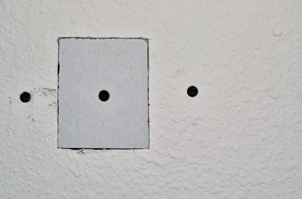 istock Drywall repairs in wall with a square repair panel. 1223476348