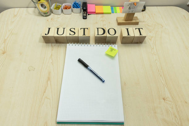 There is a notepad checker and pencil on the table. On the right, it says, Just do it, with a wooden cube. Studio was photographed.