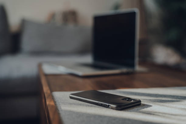 London,UK - May 5,2020: iPhone 11 Pro Max by Apple on a table at home, laptop on background, selective focus. People around the world have been working from home because of lockdown due to Coronavirus