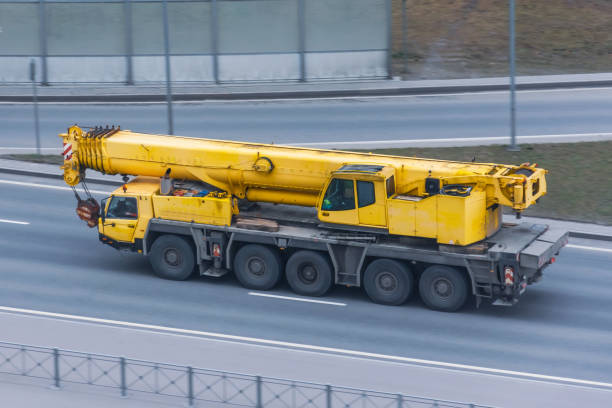 istock Heavy mobile crane with folding boom construction rides on a city highway. 1223480139
