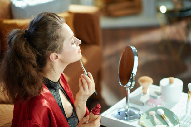 istock woman looking in mirror and using liquid foundation 1223480147