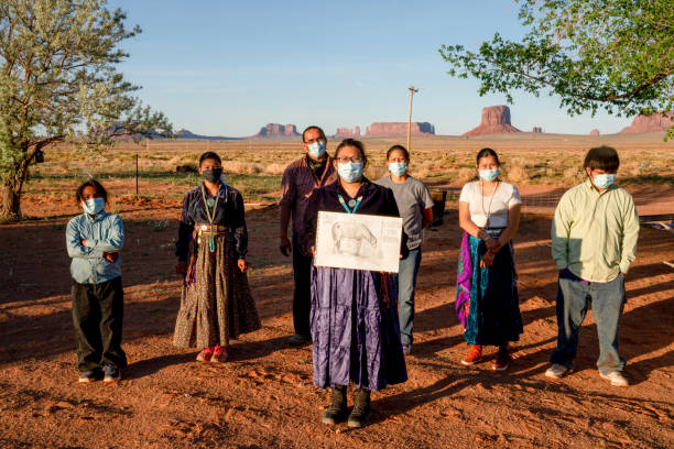 A Young Woman Holding A Drawing, With Her Family In The Background, To Help The Navajo People Understand The Severity Of Covid19 A Native American teenager holding a drawing she hoped would help her people understand the danger of coronavirus to the Navajo people navajo nation covid stock pictures, royalty-free photos & images