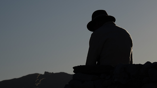 Silhouette of an unrecognizable man with hat in the dawn