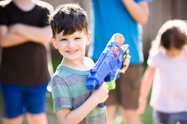 istock Young boy holding big squirt gun smiles for camera 1223480977