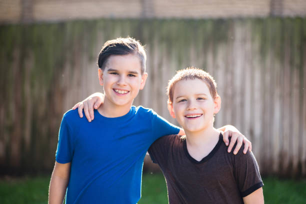 istock Two brothers stand with arms around each other in backyard 1223480978