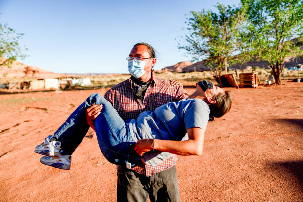 A Husband Picks Up His Wife In His Arms With Love And Laughter During The Covid19 Shutdown A Navajo husband and wife encourage one another with laughter in spite of the Coronavirus curfew by the Tribal Council in Arizona navajo nation covid stock pictures, royalty-free photos & images
